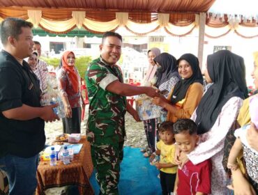 Danramil 09/NL Kapten Cba. P. Matondang, S.H., M.H saat memberikan bingkisan kepada warga dalam Program operasi katarak gratis