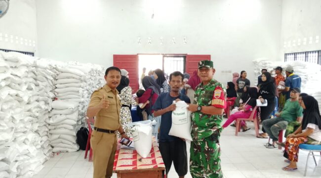 Babinsa Koramil 09/NL, Peltu Muhammad Hakim, mendampingi penyaluran bantuan pangan beras dari Bulog di Balai Kelurahan Negeri Lama, Kecamatan Bilah Hilir, Labuhanbatu